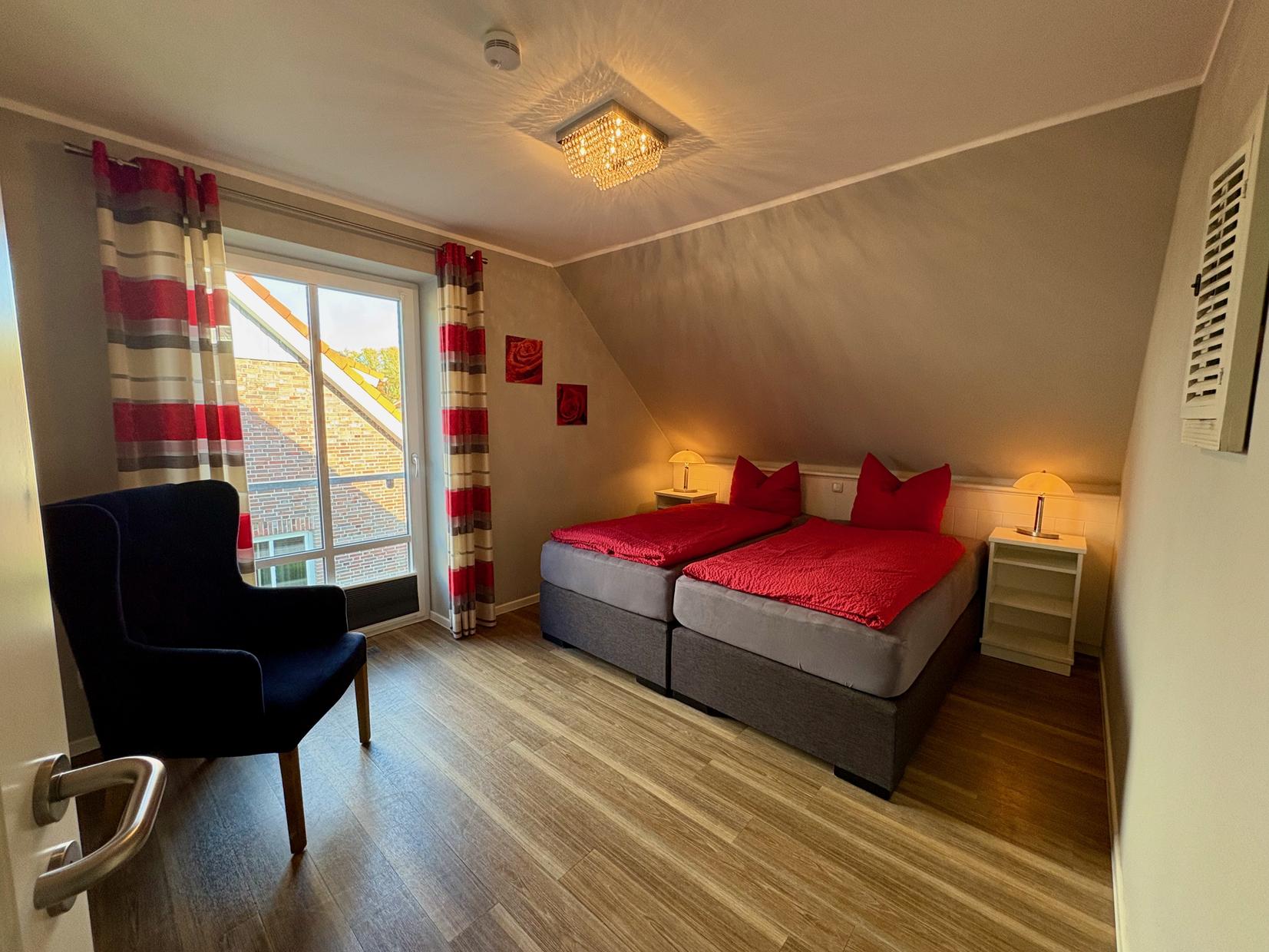 Schlafzimmer mit zwei Betten und roten Akzenten